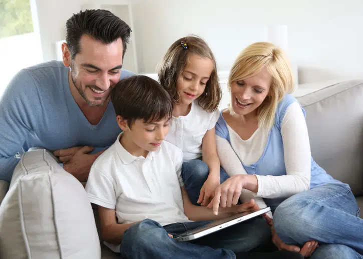 Mom and dad looking at a custom app on a tablet with their two children - USD - Social Media App Development Agency